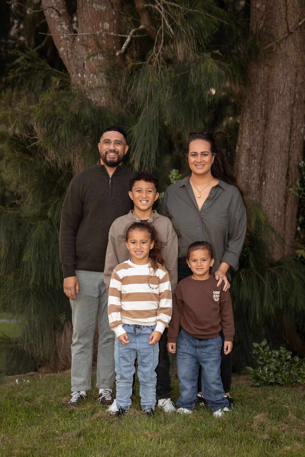 Professional family photo of Mother, father and 3 young sons posing in front of large trees. Beautiful earthy tones. Catherine Lundin Photos