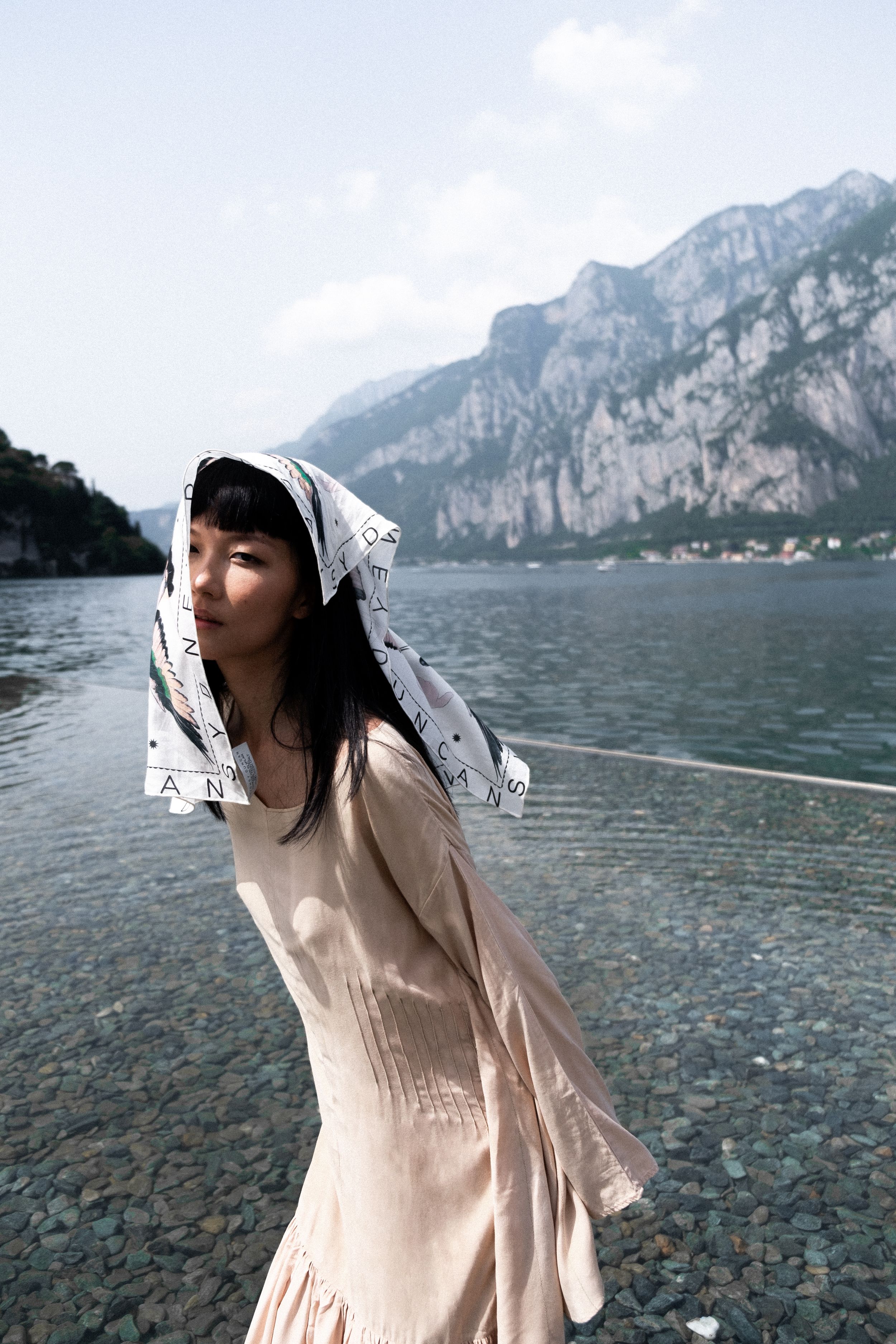 Person in a light dress poses by a scenic mountain lake.