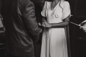 A black and white photograph showing a close-up of a couple during a wedding ceremony at Askham Hall, focused on their torsos.
