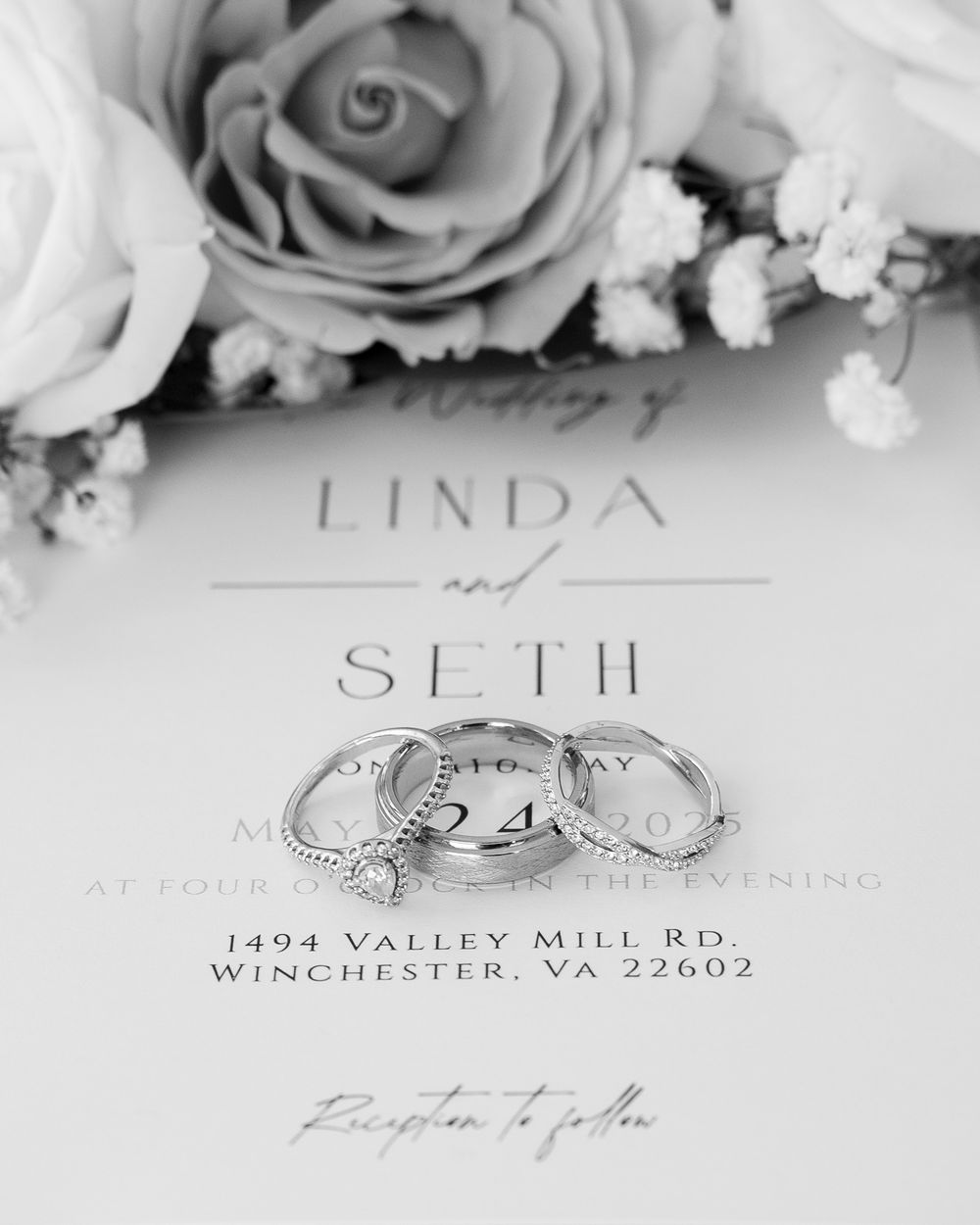 Black and white wedding invitation with wedding rings and roses showing Linda and Seth's details in elegant typography.