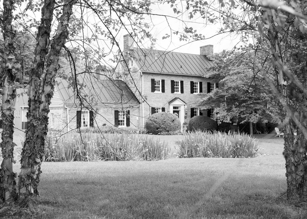 A black and white panoramic view of a historic rural property with trees and buildings stretching across the countryside.