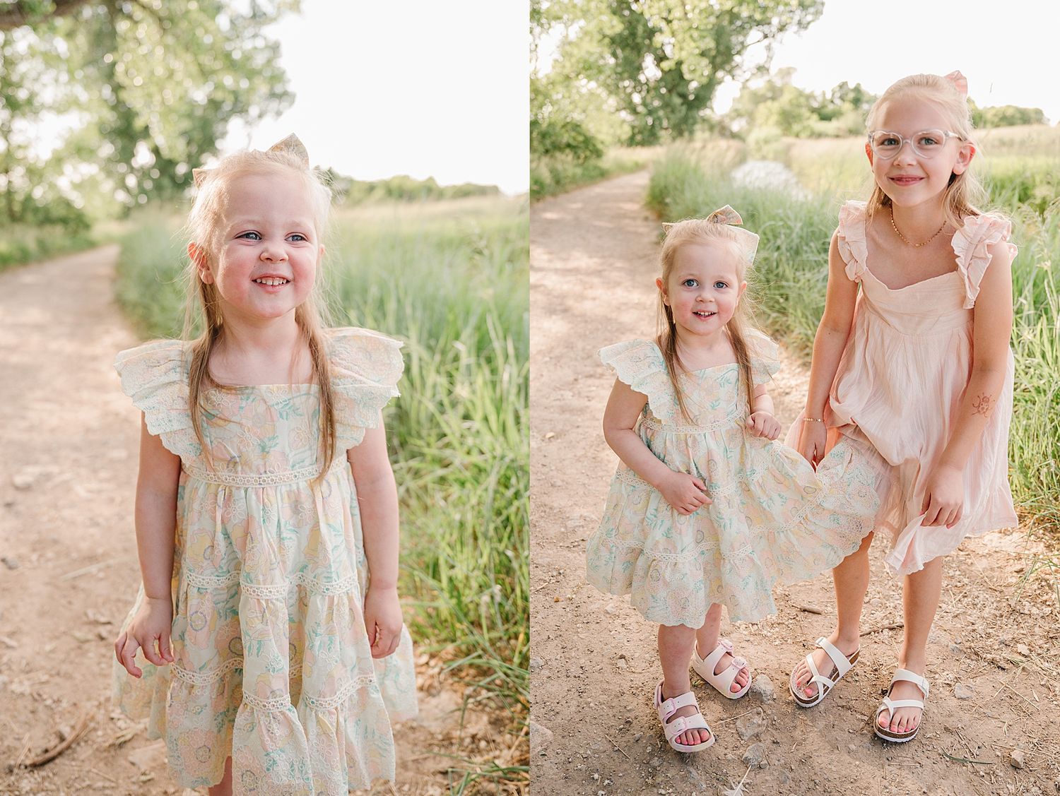 Two young children in delicate pastel dresses stand together on a dirt path surrounded by summer greenery.