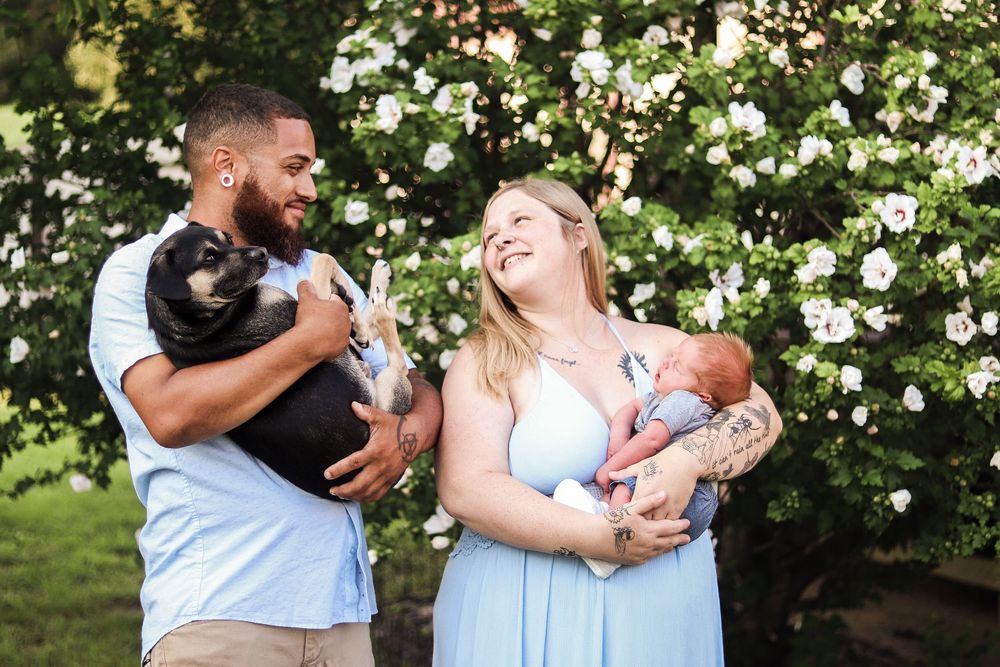 A couple shares joyful moments together in a garden setting with blooming white flowers in the background.