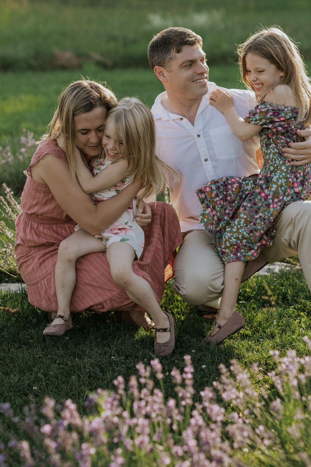 Happy family of four sharing joyful moments together in a flowering garden at sunset.