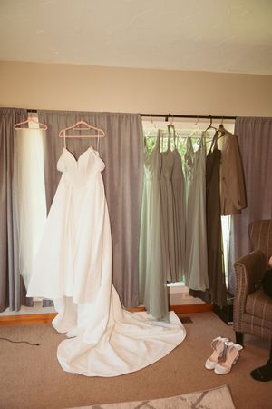 Wedding dress and bridesmaid dresses hanging on display with soft lighting.