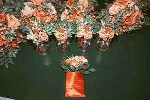 Coral and peach floral arrangements displayed in glass mason jars against a dark green background.