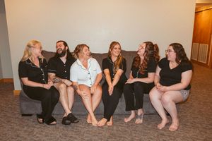 Group photo of wedding party members sitting casually on the floor.