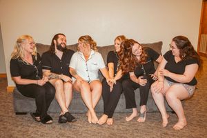 People lounging casually on floor in coordinated formal attire at a social gathering.