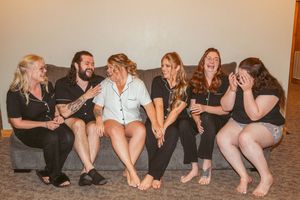A group of friends laugh together while sitting on a grey couch at a celebration.