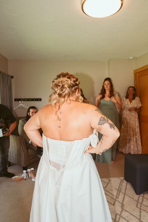 Behind the scenes moments of wedding dress preparation in a sunlit room.