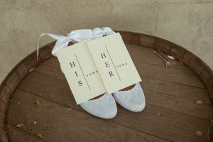 White bridal flats and letter decorations arranged on wooden barrel top.