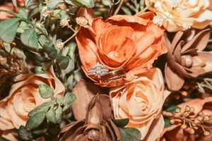 Close-up of peach and coral roses with green foliage in wedding floral arrangement.