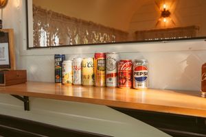 Bar shelf display with various bottles and drinks lined up under warm lighting.