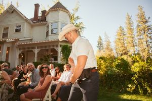 Performer entertaining outdoor crowd at sunset in front of Victorian style house on warm summer evening.
