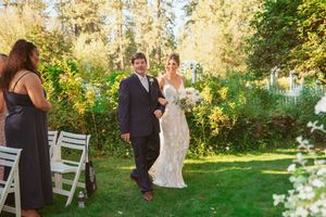 A panoramic view of a lush garden wedding ceremony with white chairs set up on a green lawn.