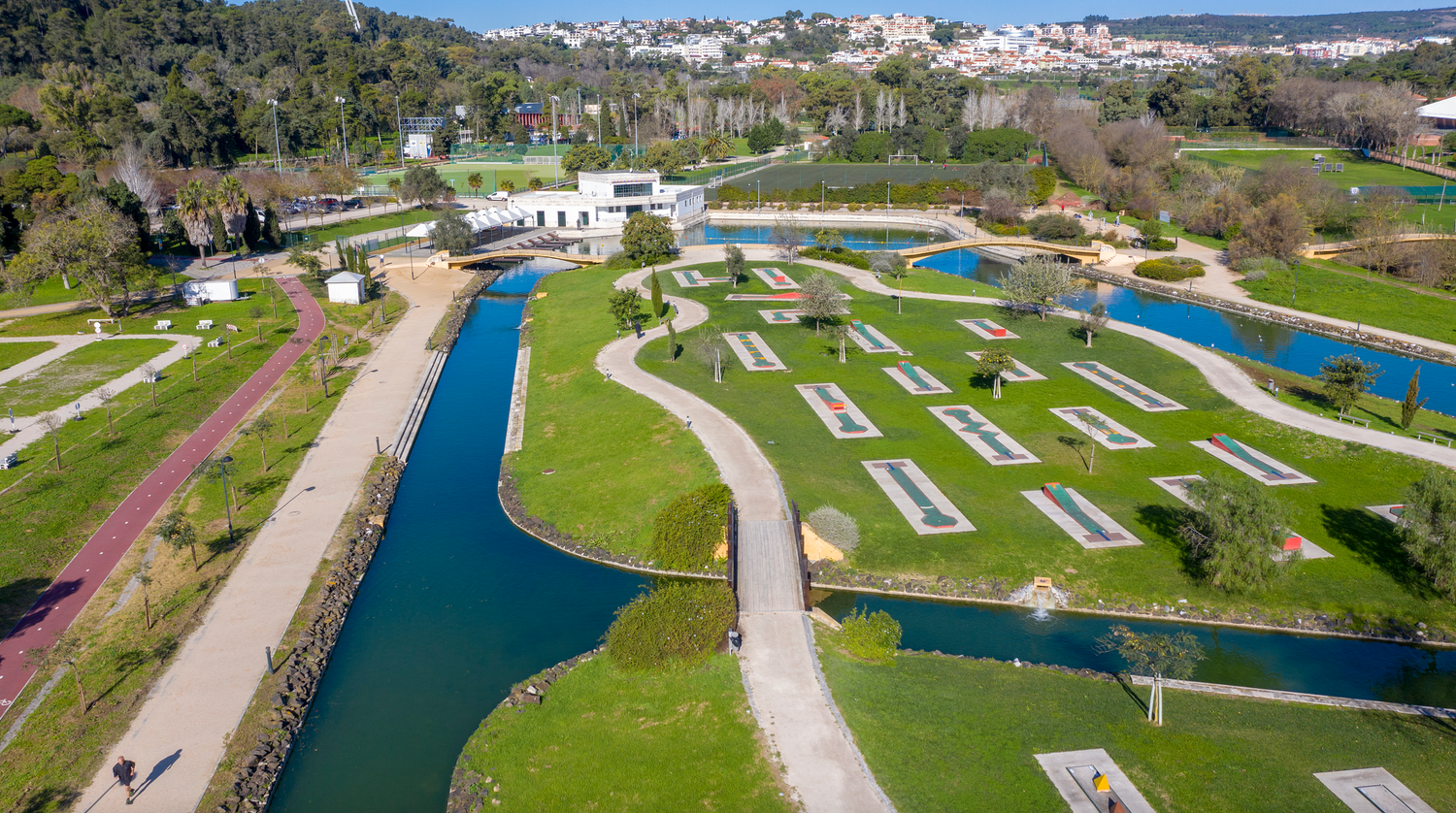 Aerial panorama of golf course with winding water features and manicured greens.