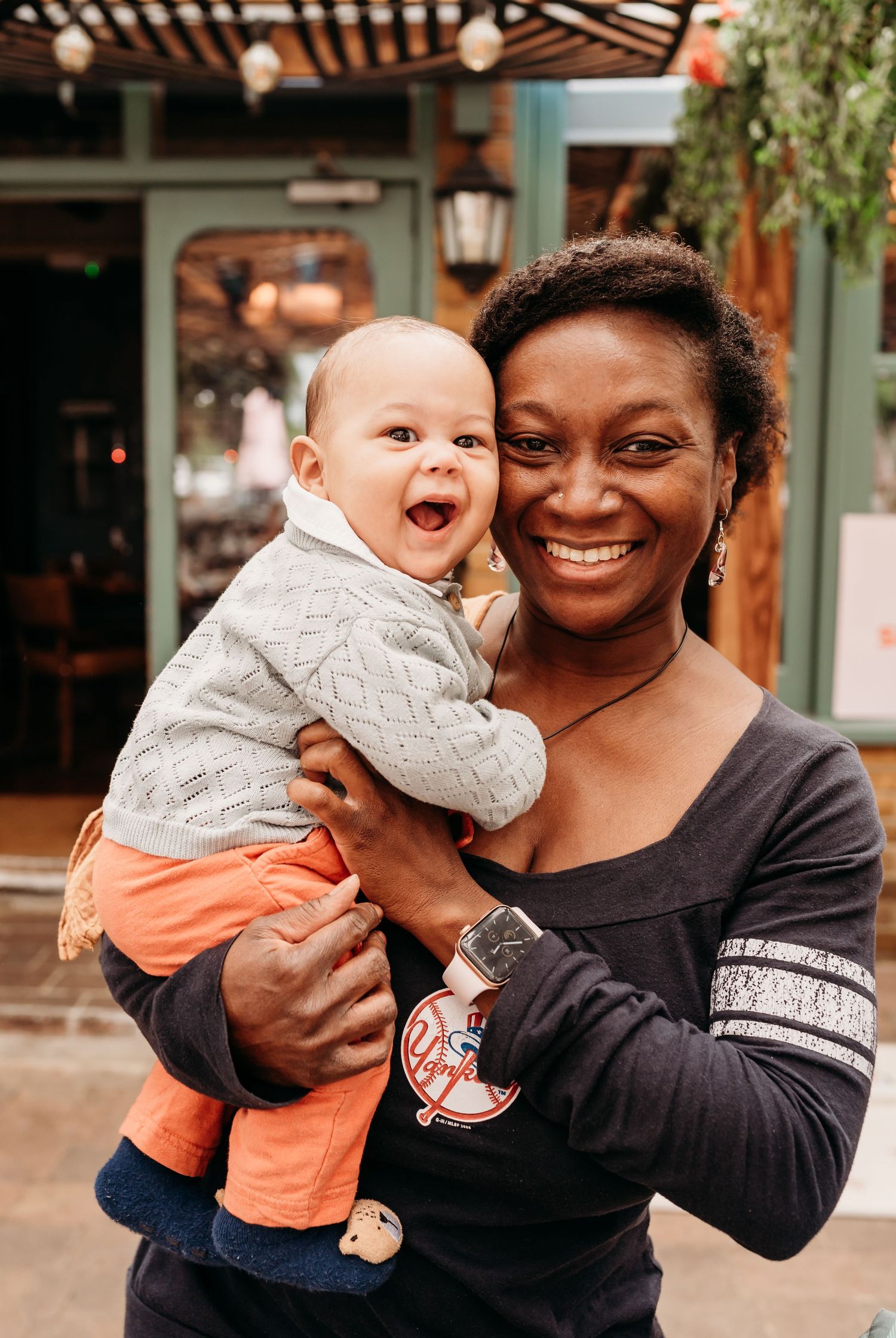Heartwarming moment of joy shared between a baby in gray sweater and orange pants at an outdoor venue.