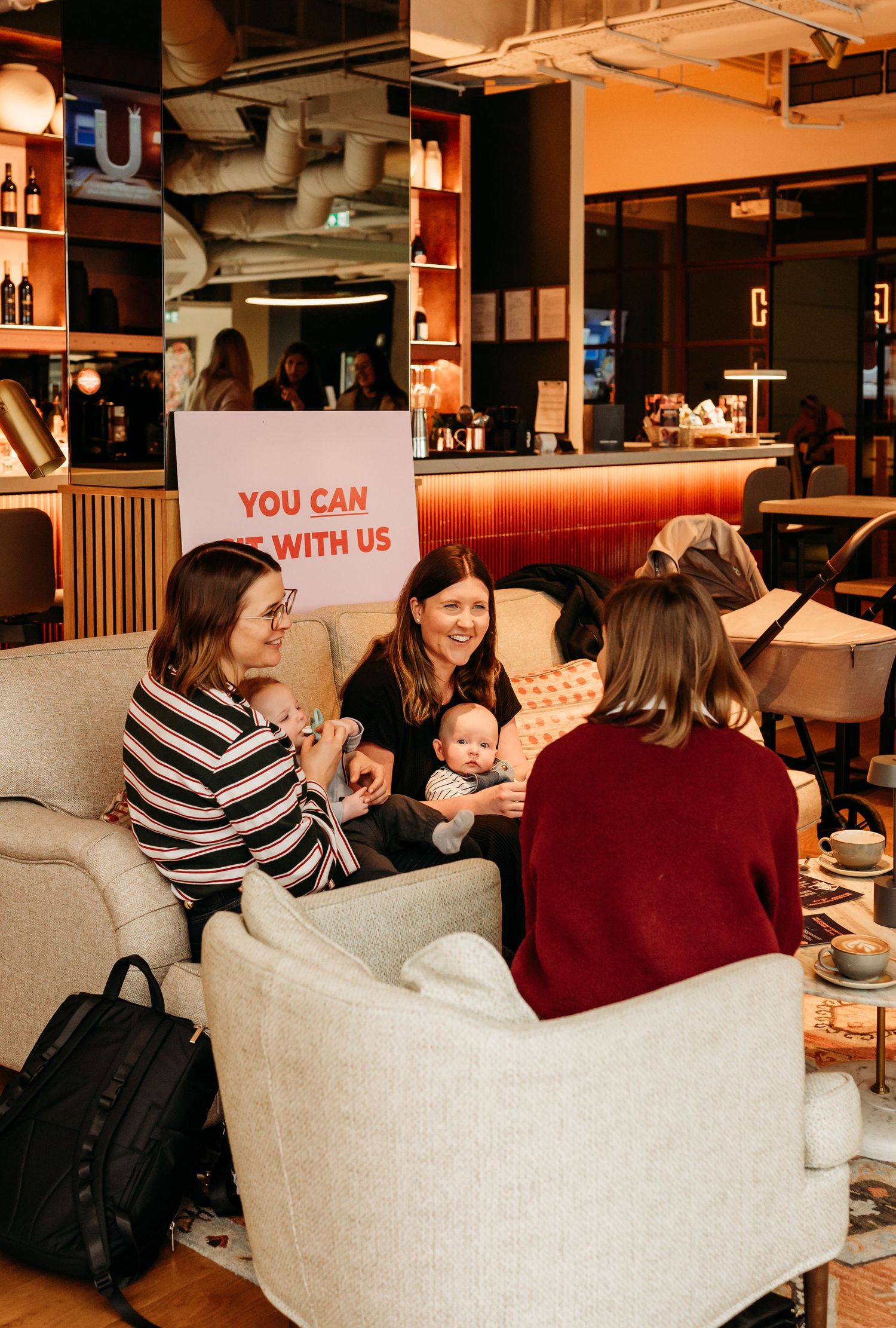 A cozy cafe setting with groups of people gathered around tables enjoying coffee and conversation together.