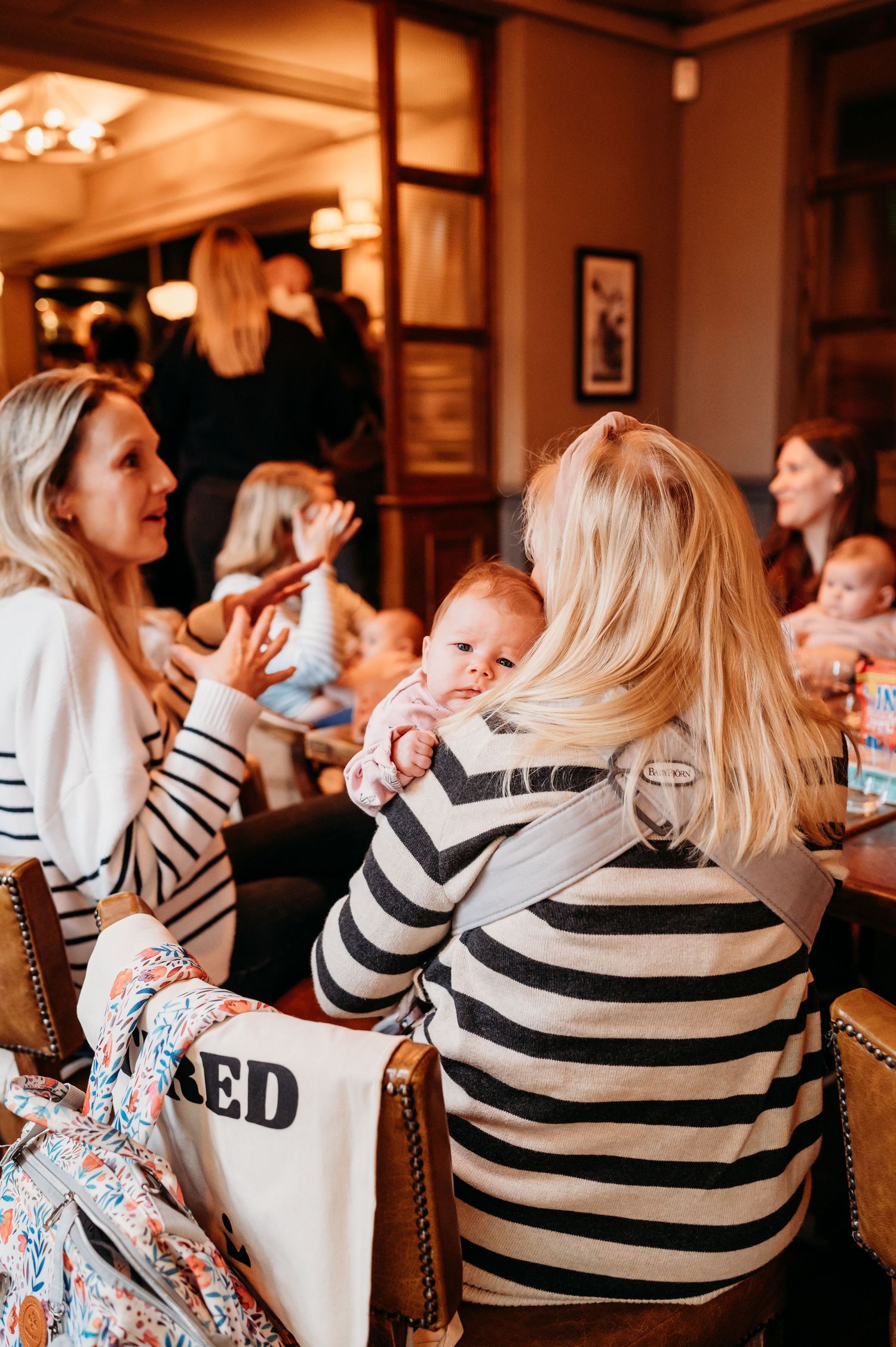 Warm-lit restaurant gathering with people in striped shirts seated at tables marked 'TIRED'.