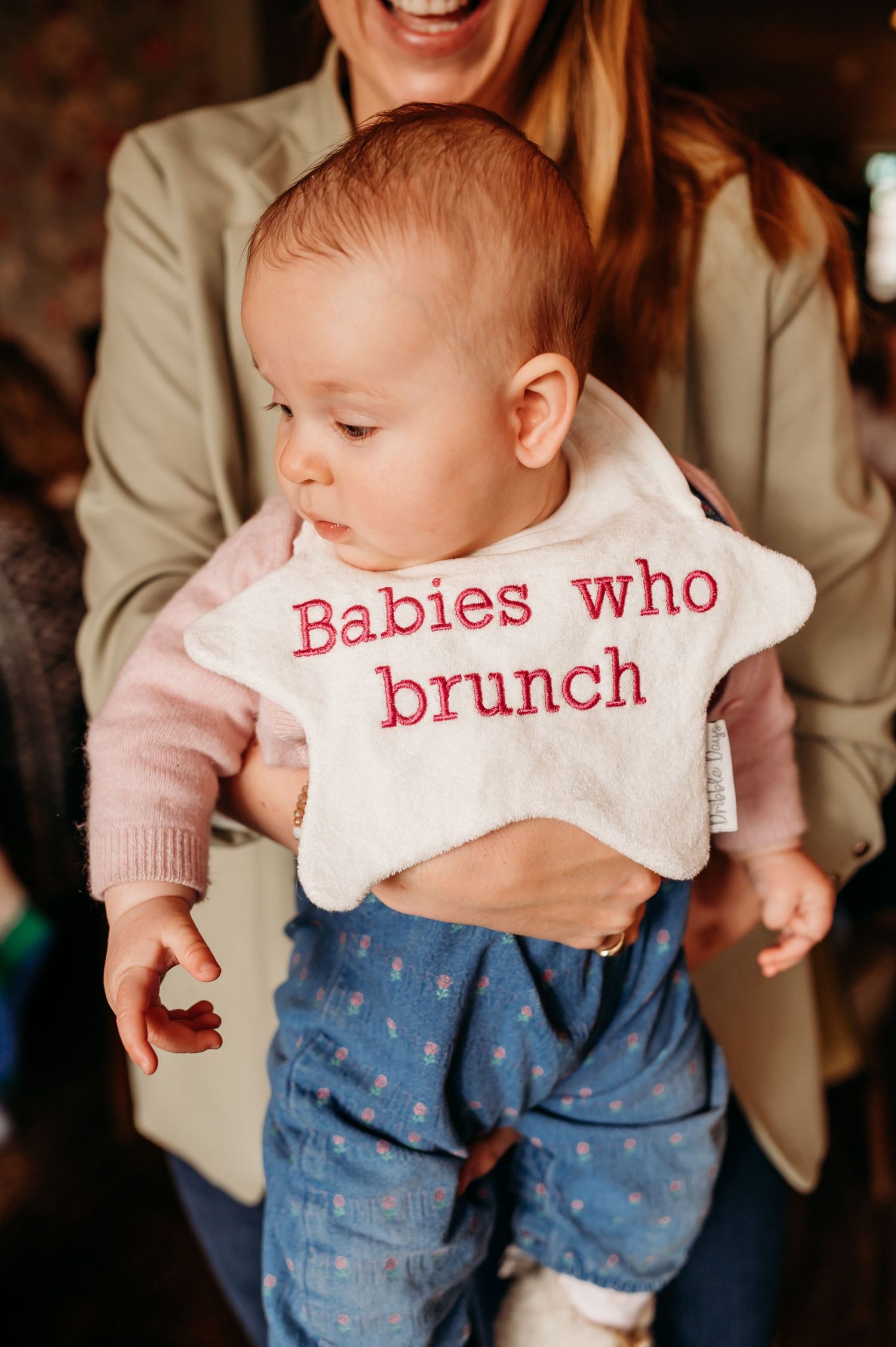 A series of connected photos showing a baby wearing a white bib with red lettering and blue patterned pants.