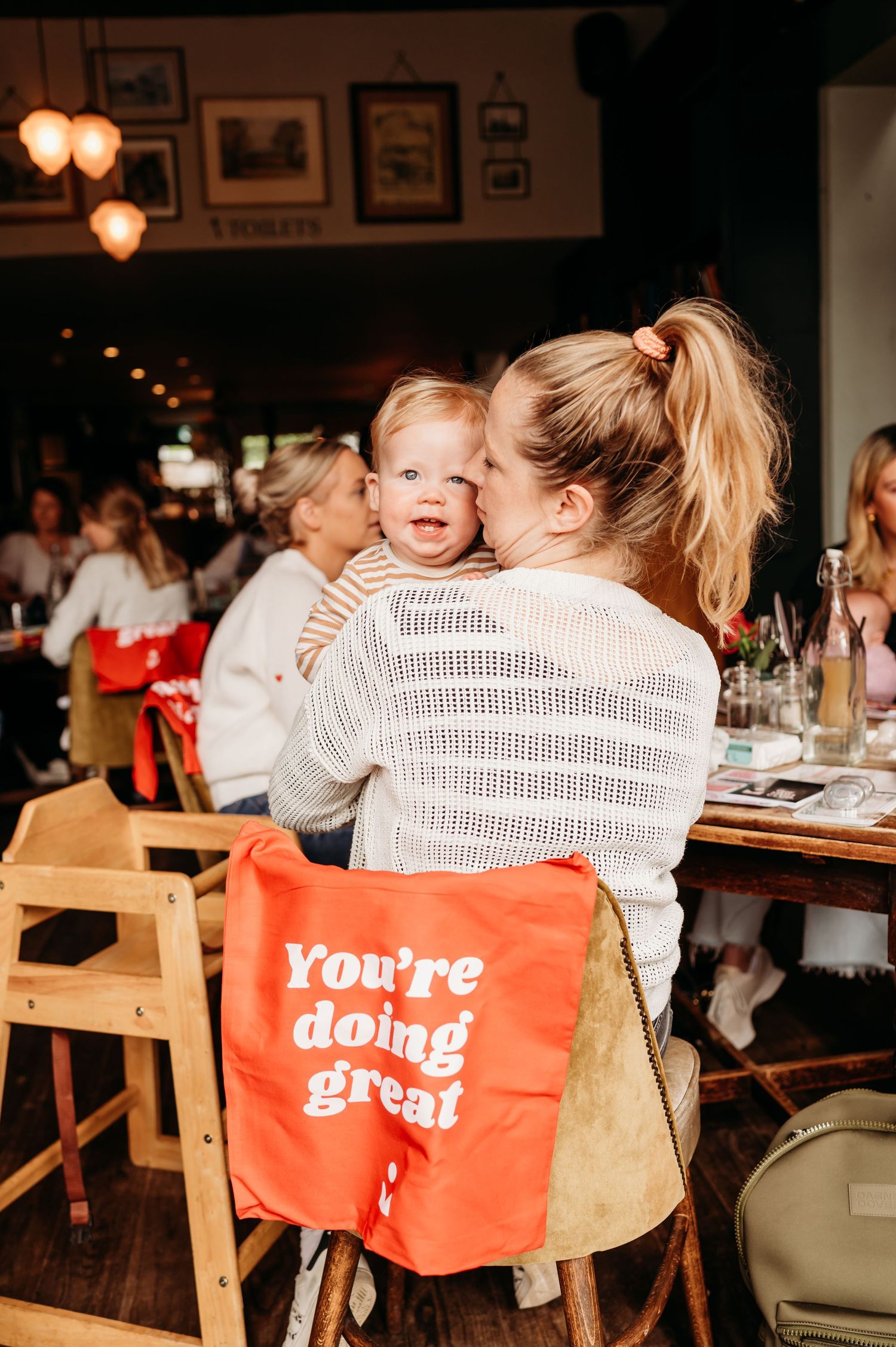 Red chair signs with positive messages arranged at a restaurant table during a casual social gathering.