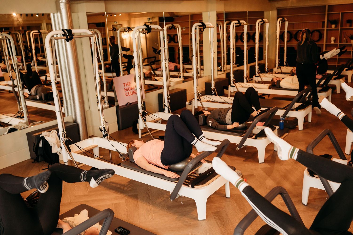 Modern fitness center interior with weight machines and exercise equipment arranged in rows with mirrored walls.
