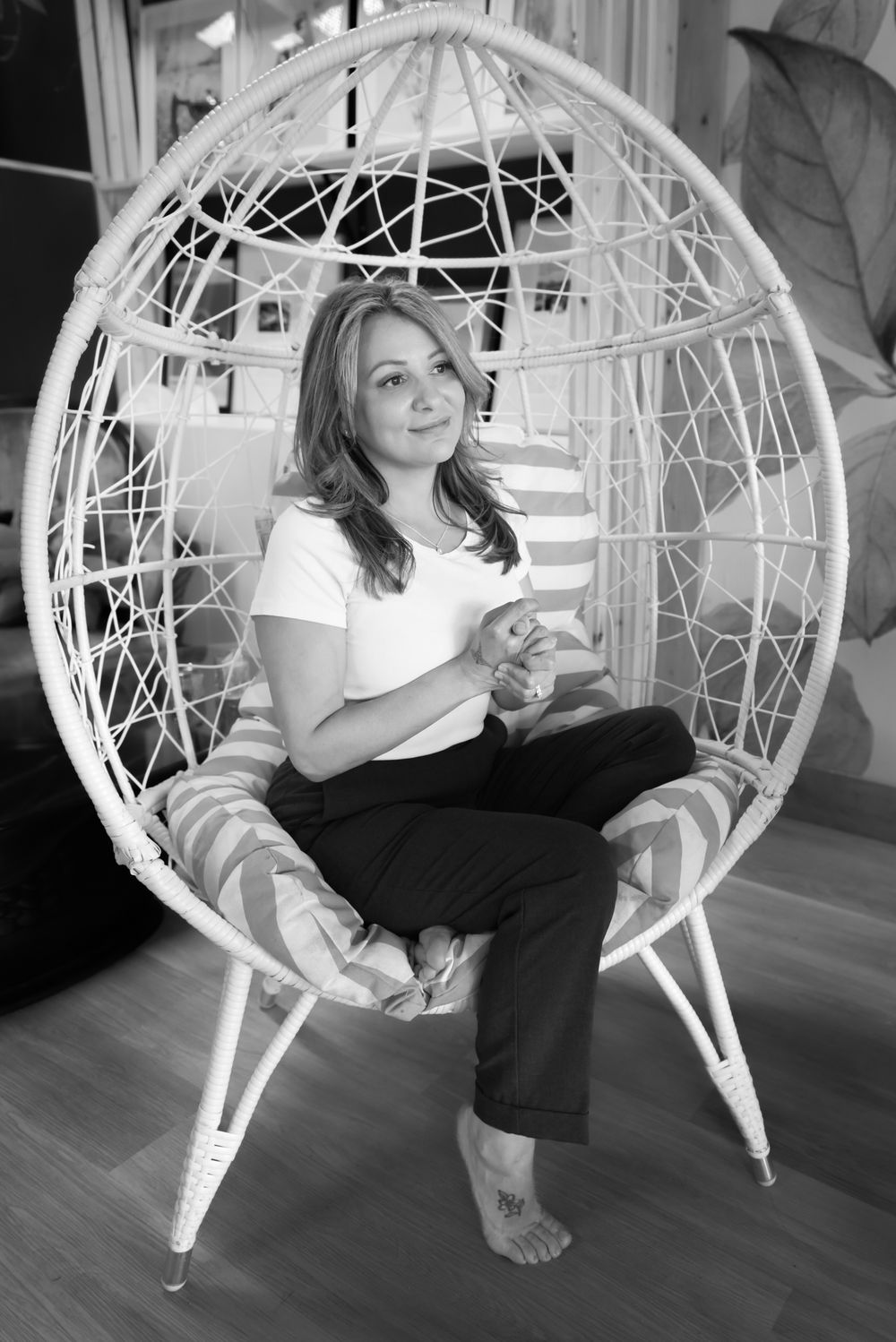 Lifestyle photos in a white wicker hanging chair against hardwood floors.