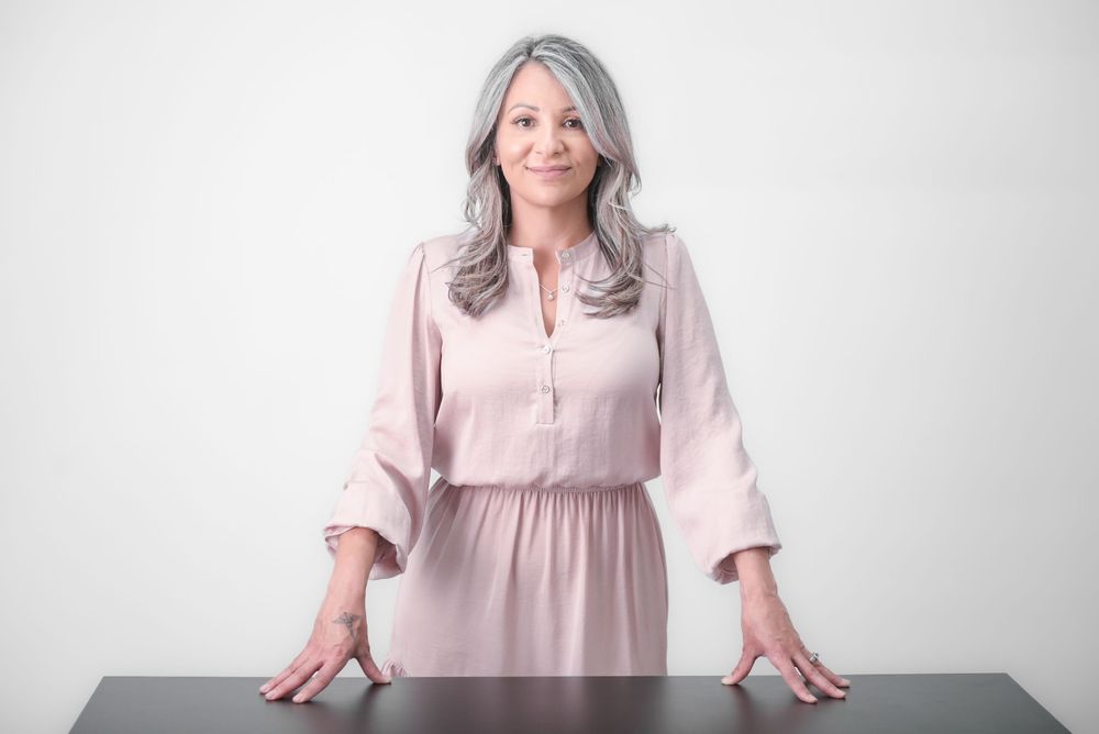 Professional headshots in a pale pink blouse against a white background.