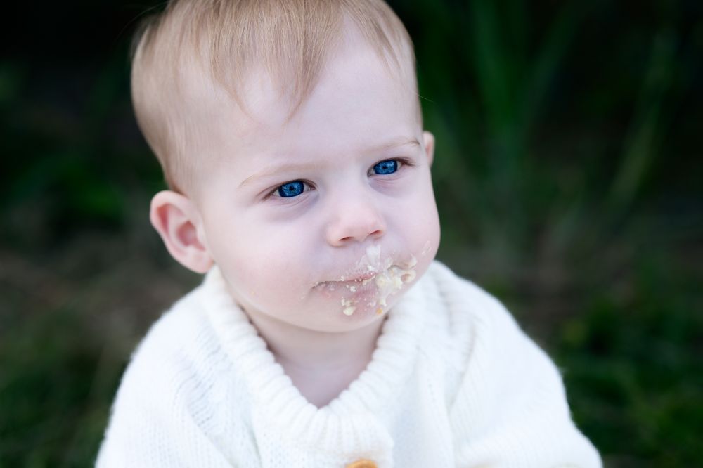 Baby with chocolate or food smeared on their face in multiple expressions against dark background.