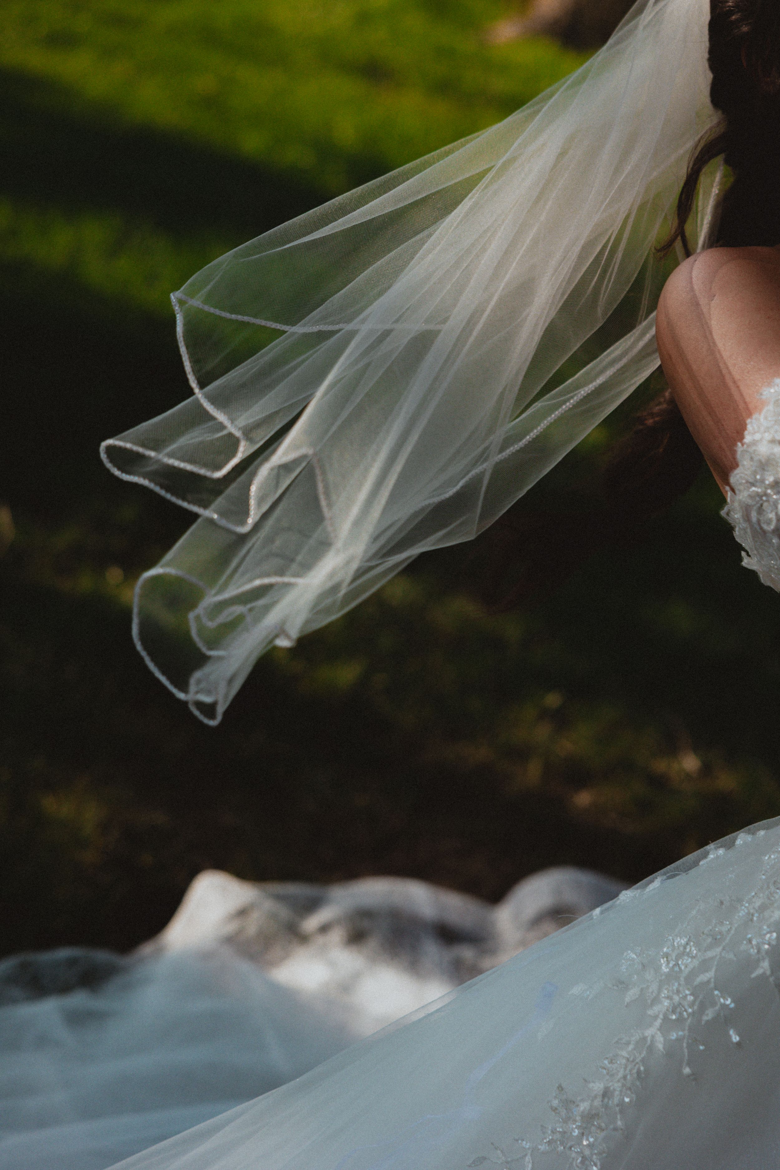 Flowing white wedding veil billowing in the breeze against a natural outdoor background.