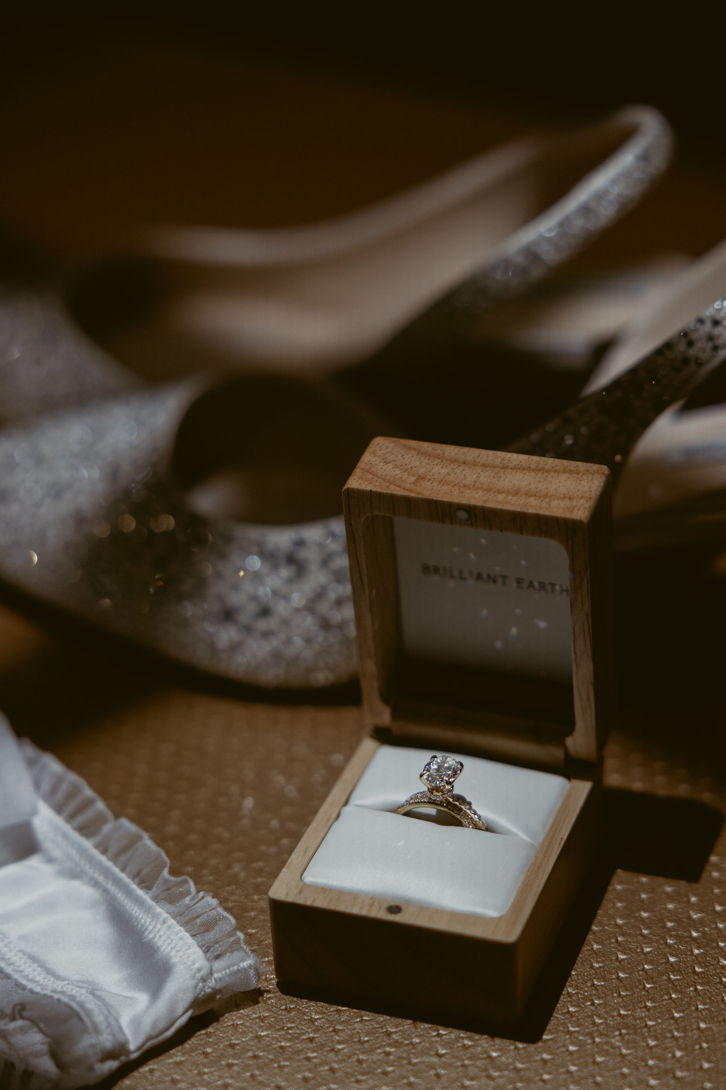 Close-up of an engagement ring in a wooden box with delicate details.