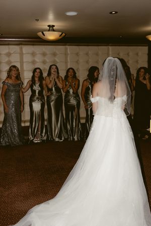 Wedding party members in formal attire lined up against an elegant indoor backdrop.