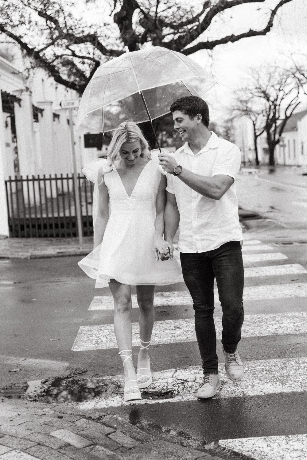 Black and white image of two people with white umbrellas walking close together on a paved path, shown four times.