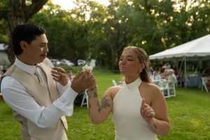 Wedding celebration moment on a lawn with white tent and summer greenery in background.