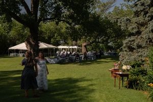 Outdoor wedding venue setup with chairs and tents visible through trees.