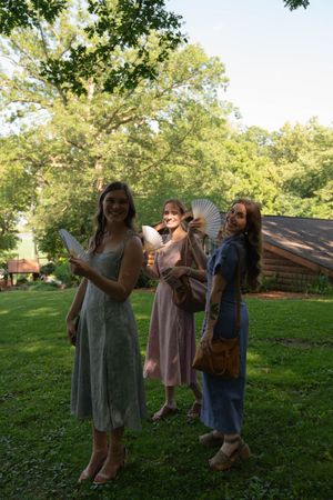 Wedding guests in summer dresses pose together on a grassy lawn.