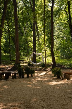 Wooded outdoor wedding ceremony site with wooden benches arranged in rows.