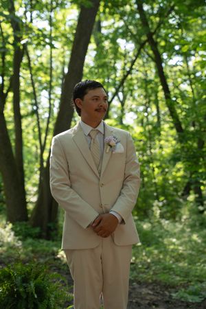 Groomsmen in matching cream suits pose in a wooded outdoor setting.