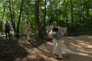 A wedding ceremony takes place on a natural forest path with dappled sunlight.