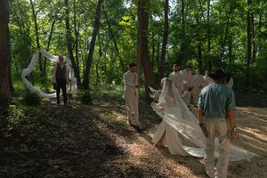 Sunlight filters through trees during an outdoor wedding ceremony in a wooded setting.