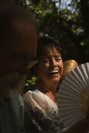 A decorative fan creates a joyful moment during outdoor wedding celebrations.