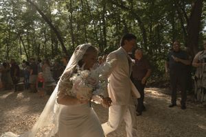 A romantic wedding moment captured in a natural forest setting with dappled sunlight.
