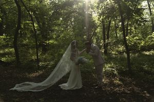 Sunlight streams through trees during an outdoor forest wedding ceremony.