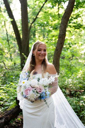 A beautiful bridal portrait in a lush forest setting with a colorful bouquet.