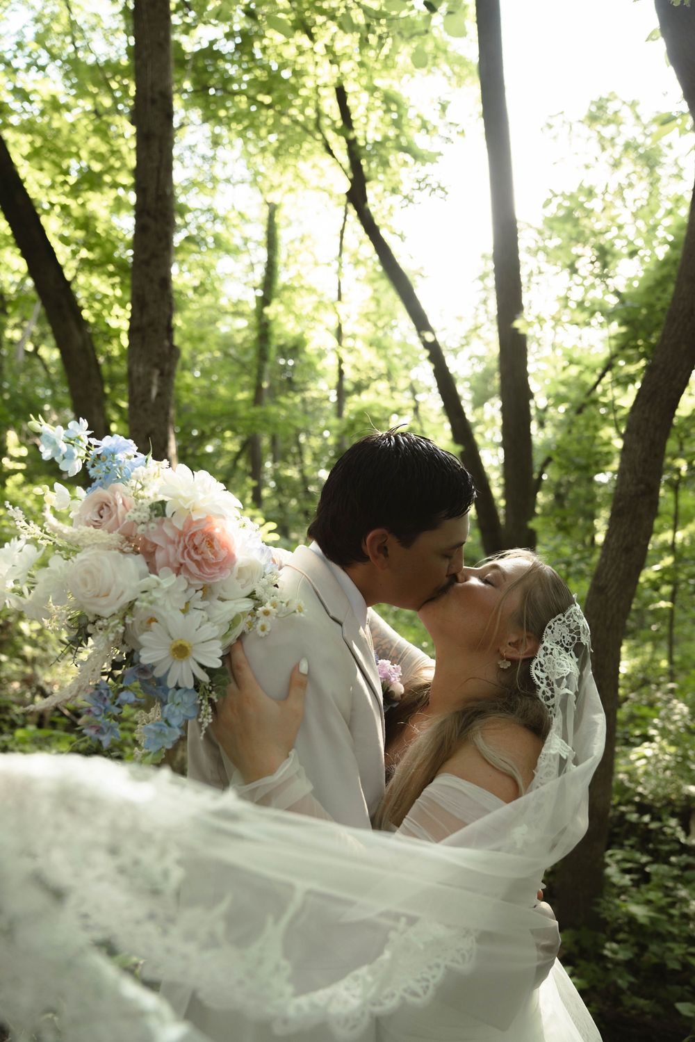 Flowing white wedding dress captured in motion against a wooded backdrop.