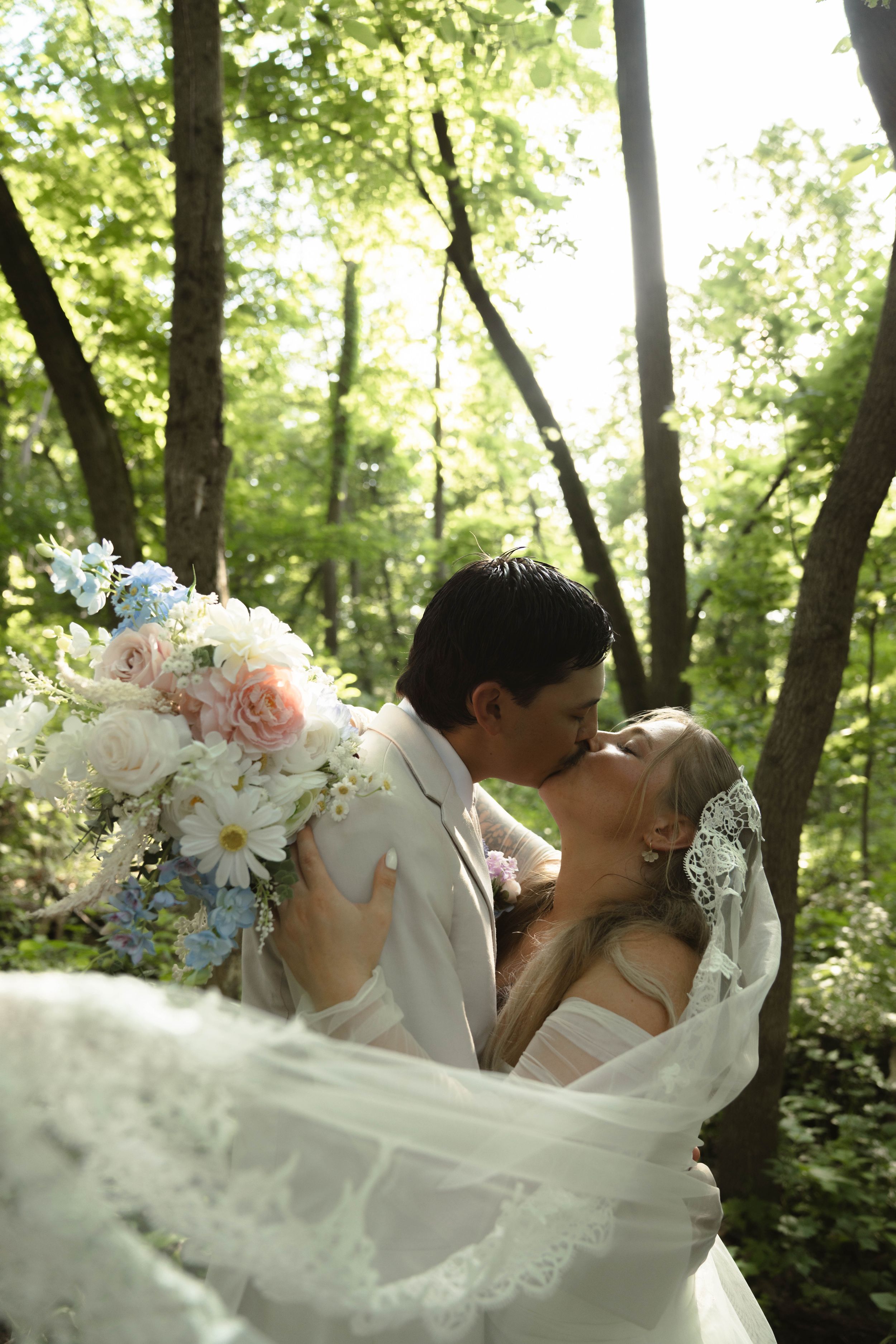 Flowing white wedding dress captured in motion against a wooded backdrop.