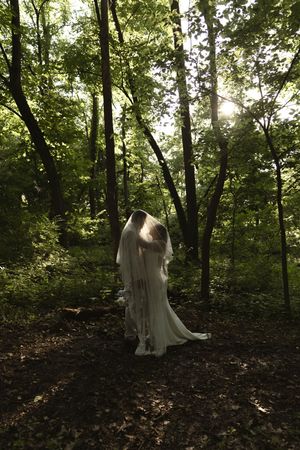 An ethereal bridal portrait session in a forest with sunlight filtering through the trees.