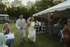 Guests mingle and celebrate at an outdoor wedding reception under white tents.