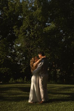A couple shares an intimate moment during golden hour at their outdoor wedding.