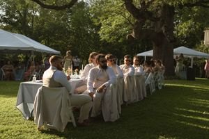Wedding guests seated at decorated tables under white tents during an outdoor reception.